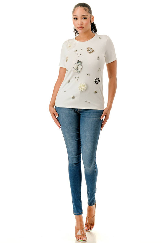 Woman wearing a white t-shirt with floral designs and blue jeans on a white background Born To Glam