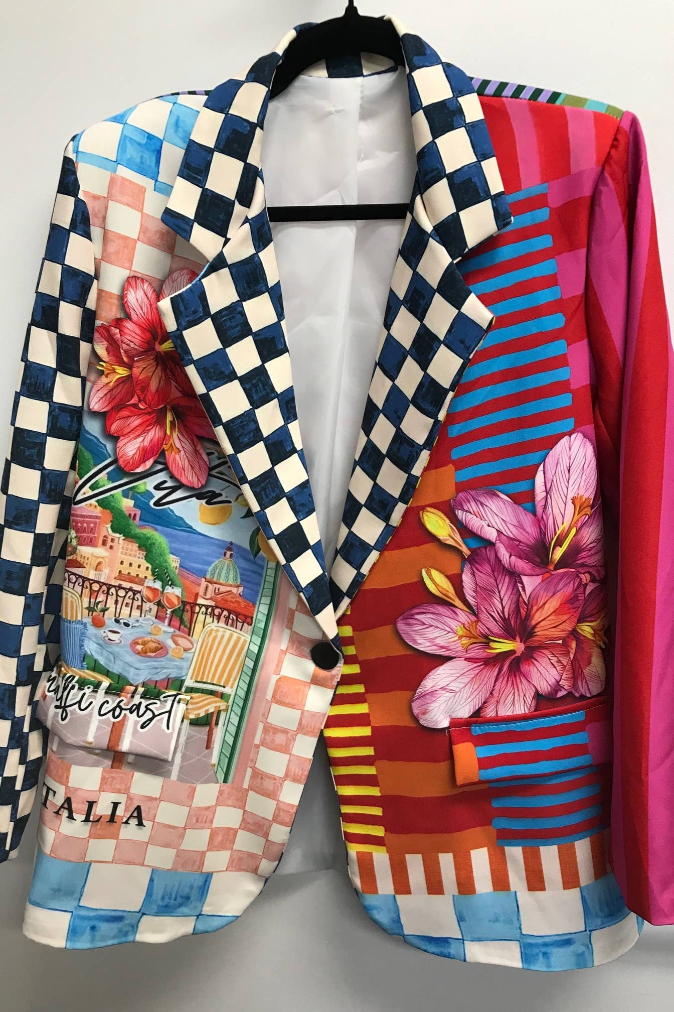 Colorful checkered blazer with floral and landscape designs on a mannequin against a white background Born To Glam