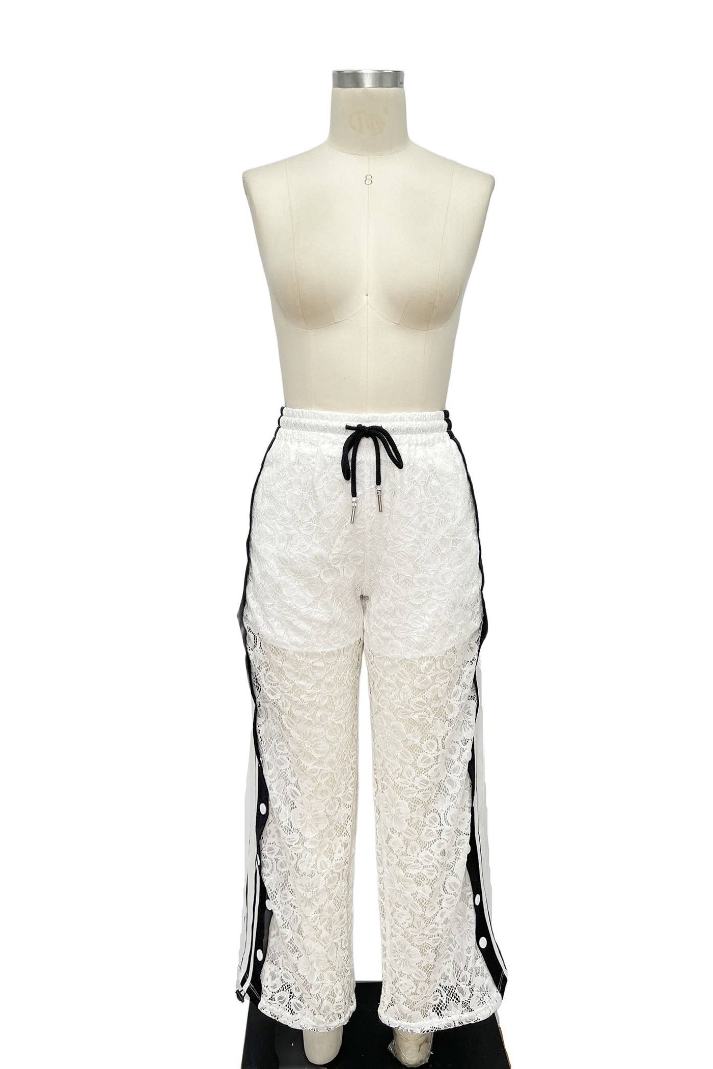White lace pants with black accents on a mannequin against a white background Born To Glam