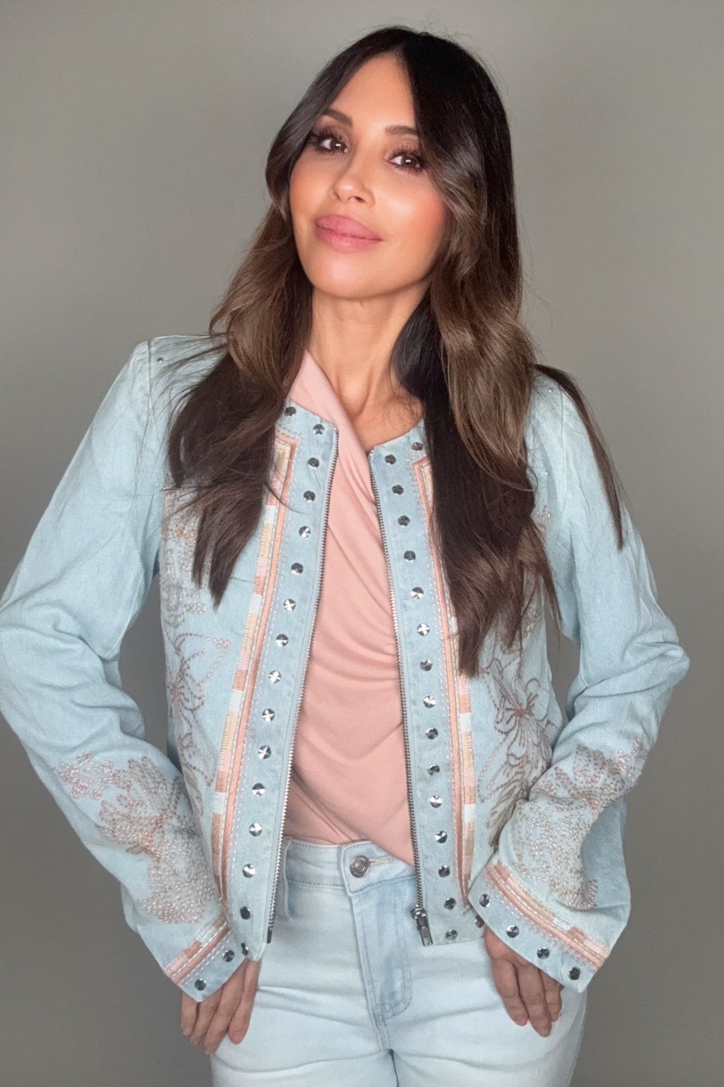 Woman wearing a light blue jacket with lace details on a plain background Born To Glam