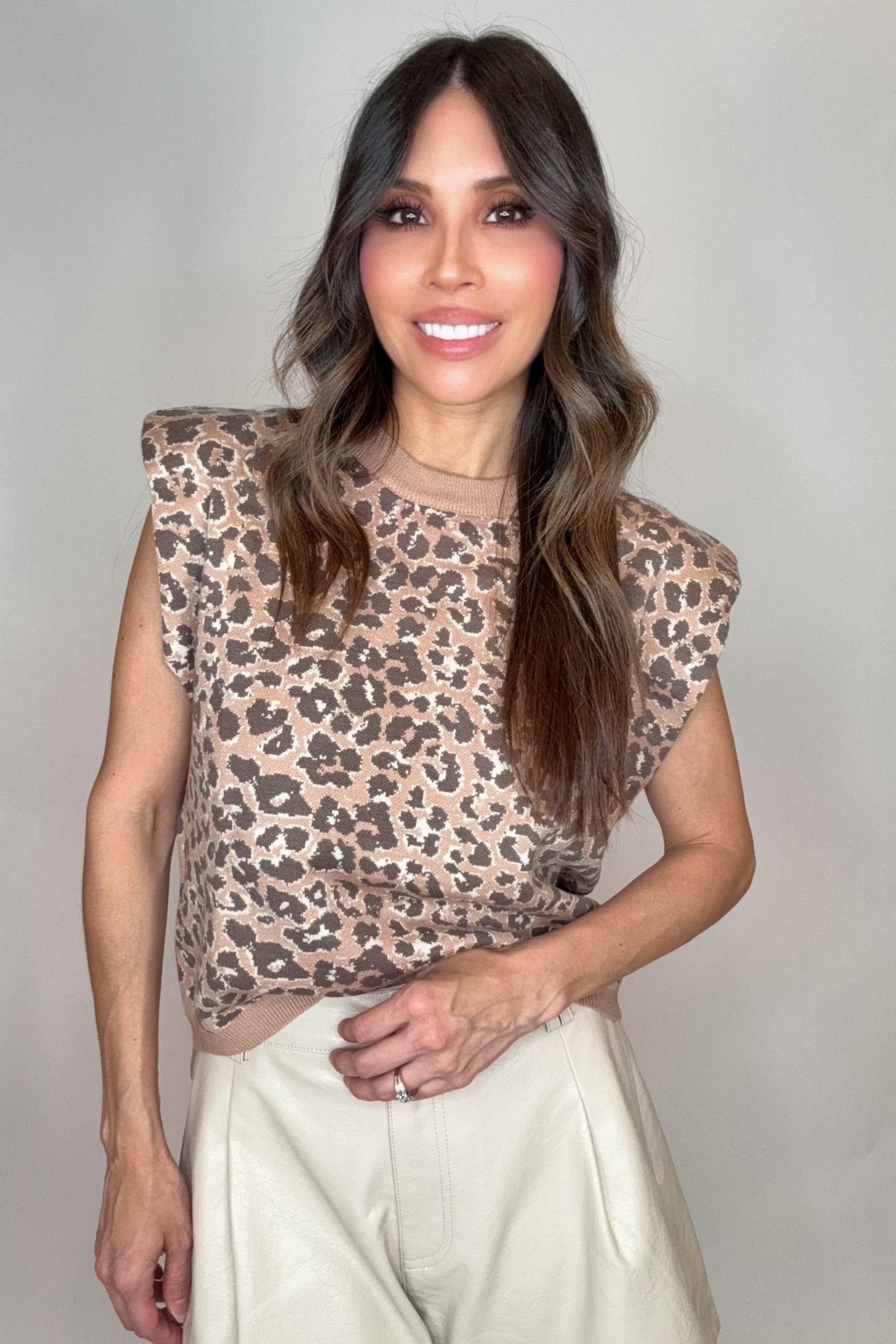 Woman wearing a leopard print top and light-colored pants against a plain background Born To Glam