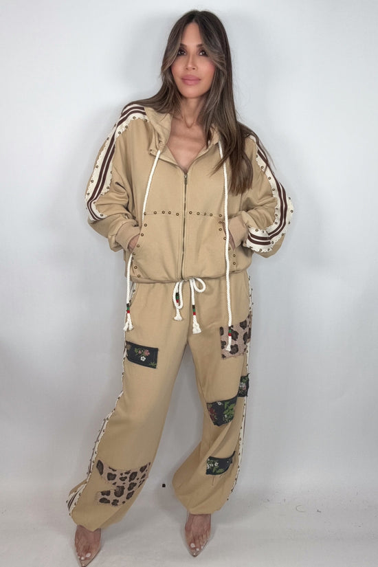 Woman wearing a beige tracksuit with leopard print details on a white background Born To Glam