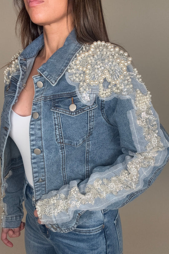 Denim jacket with pearl embellishments worn by a person against a neutral background Born To Glam