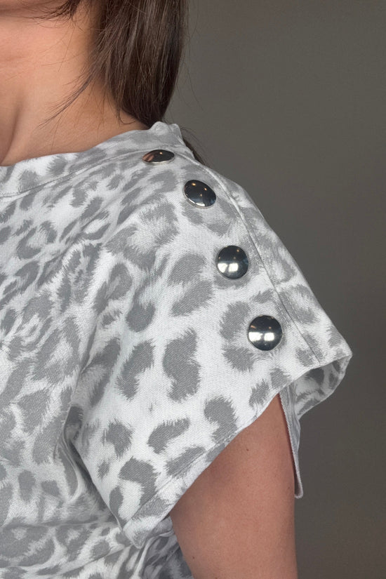 Person wearing a gray leopard print jacket with black buttons on a plain background Born To Glam