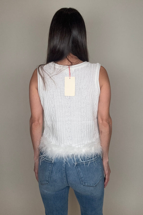 Person wearing a white sleeveless top and blue jeans against a plain background Born To Glam