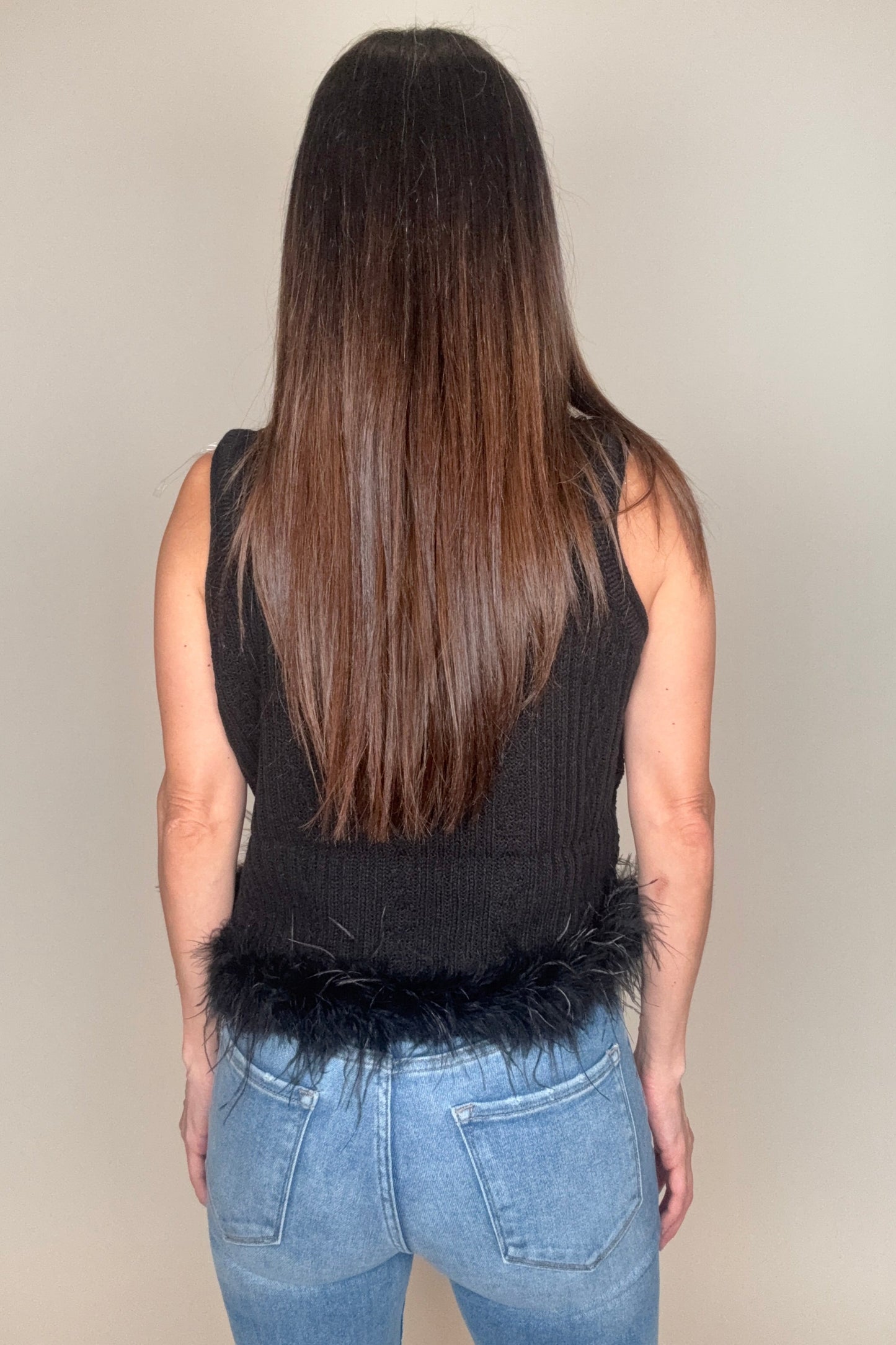 Person holding a long black wig against a neutral background Born To Glam