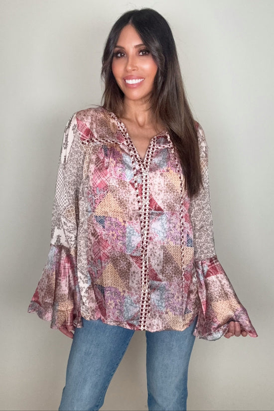 Woman wearing a patterned blouse and jeans against a plain background Born To Glam