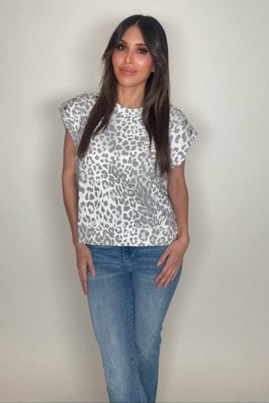 Woman wearing a leopard print top and jeans against a plain background Born To Glam