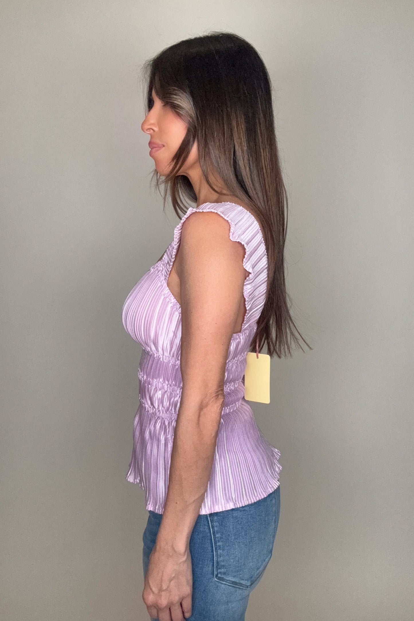 Woman wearing a purple sleeveless top with ruffled details against a plain background Born To Glam