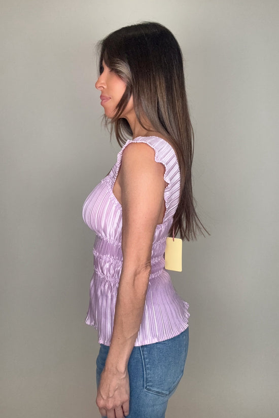Woman wearing a purple sleeveless top with ruffled details against a plain background Born To Glam