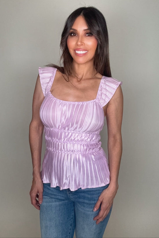 Woman wearing a light purple top with ruffled sleeves against a plain background Born To Glam