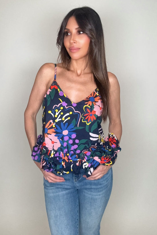 Woman wearing a colorful floral top and blue jeans against a plain background Born To Glam