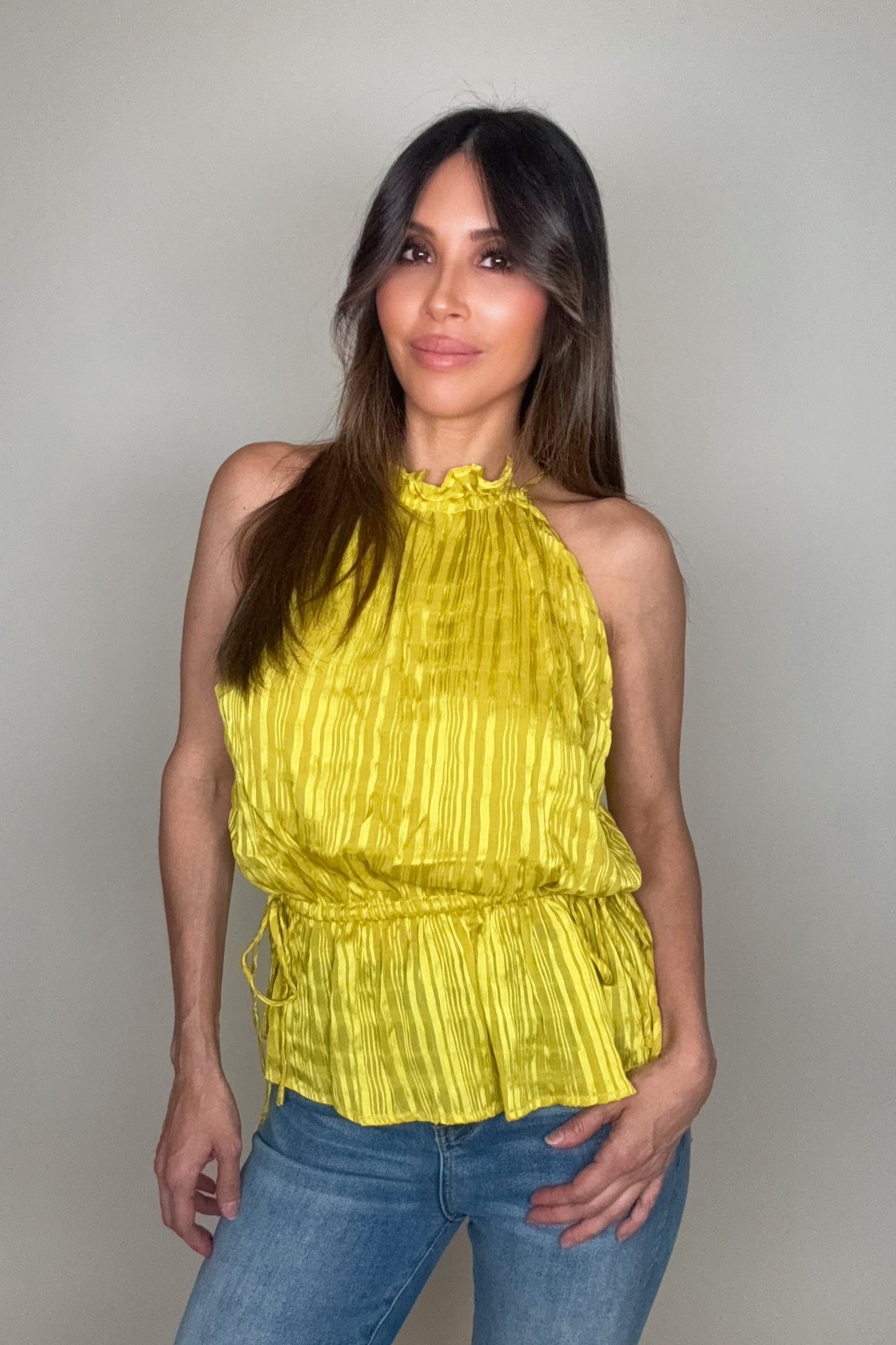 Woman wearing a yellow top and blue jeans against a plain background Born To Glam