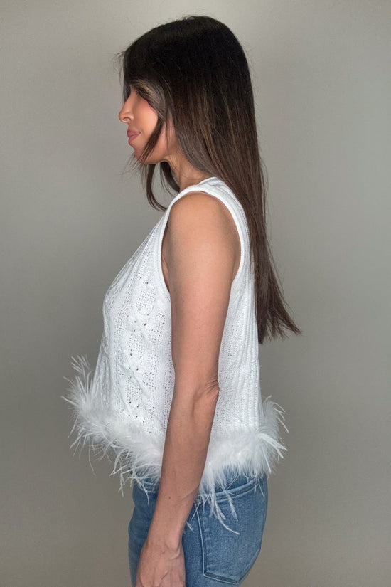 Woman wearing a white sleeveless top with feather details on a plain background Born To Glam