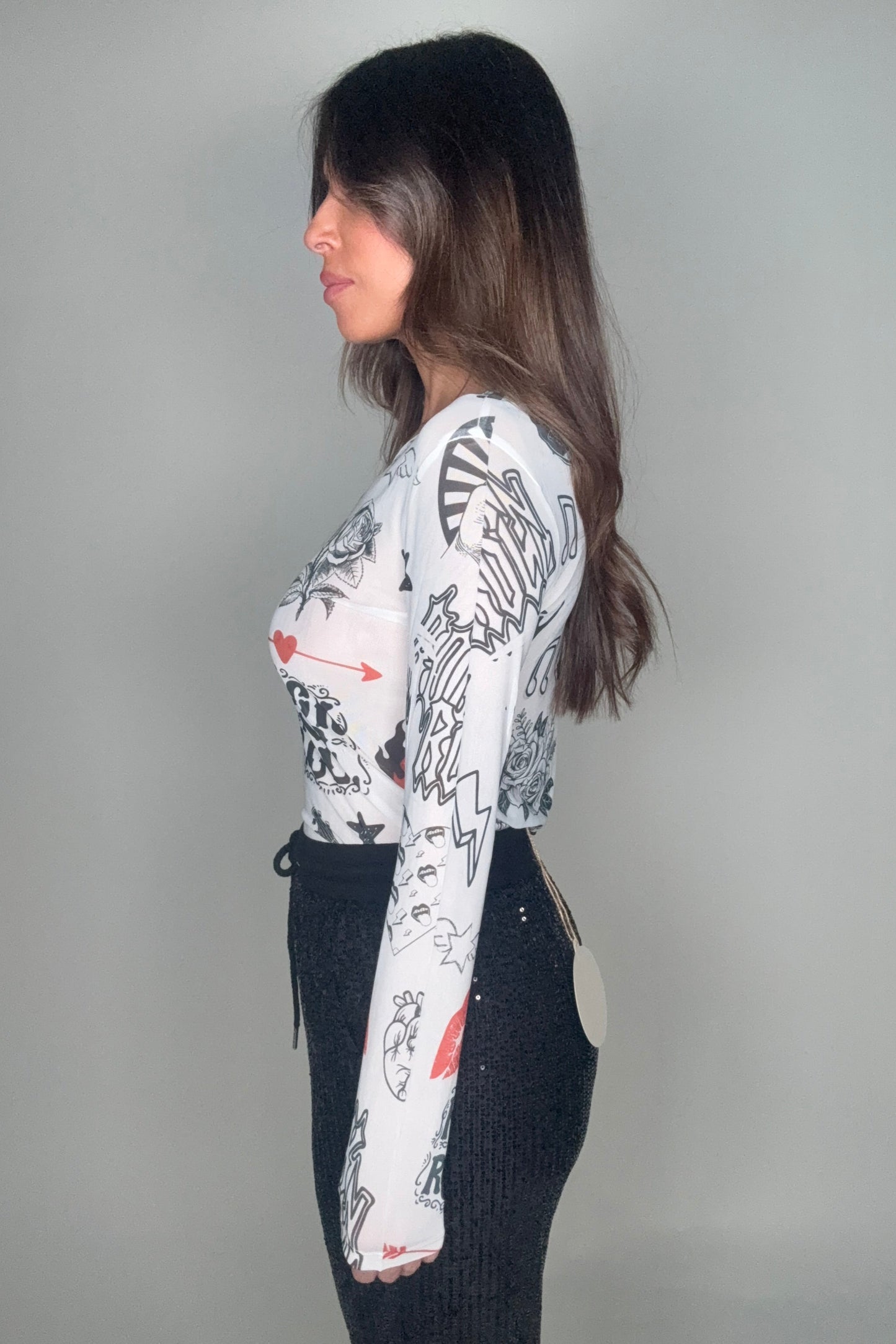 Person wearing a white shirt with black and red designs on a gray background Born To Glam