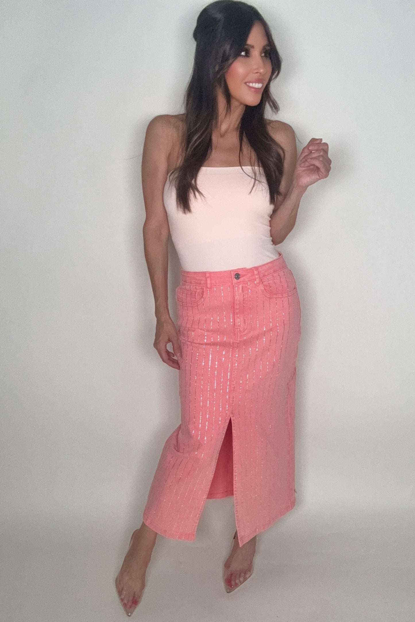 Woman wearing a pink skirt and white top on a plain background Born To Glam