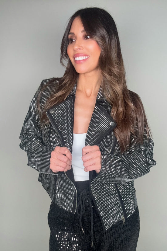 Woman wearing a sparkling black jacket against a plain background Born To Glam