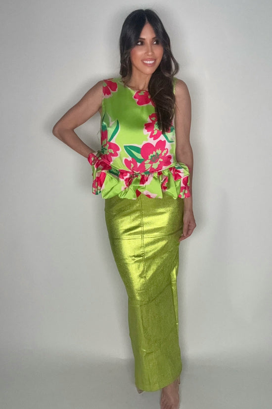 Woman wearing a green floral top and green skirt against a plain background Born To Glam