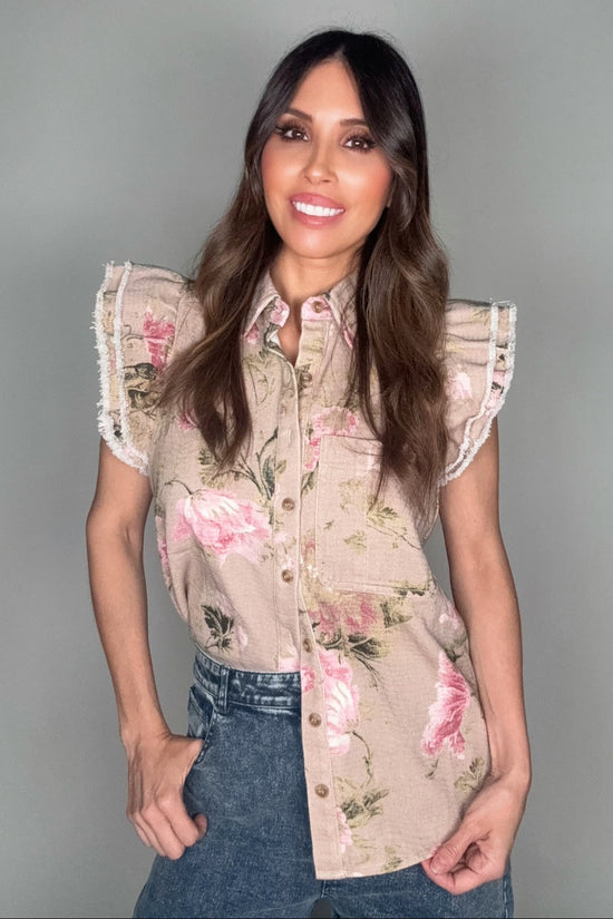 Woman wearing a floral blouse with ruffled sleeves against a plain background Born To Glam