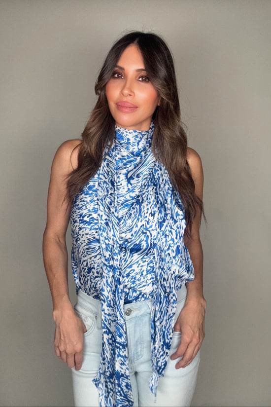 Woman wearing a blue patterned top against a plain background Born To Glam