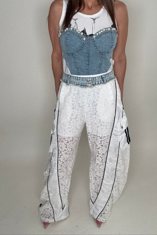 Person wearing a white lace dress with denim accents on a plain background Born To Glam