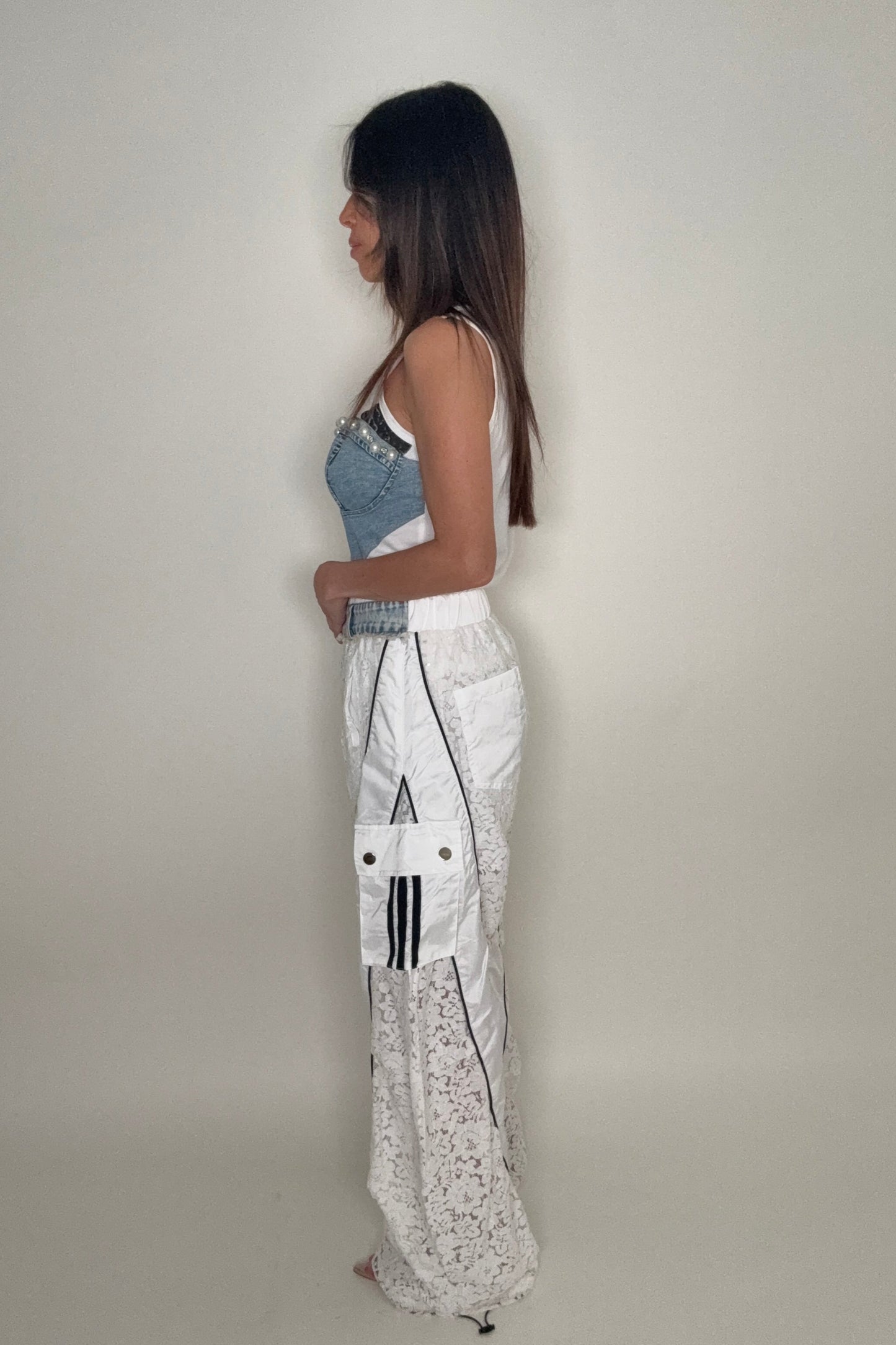 Person wearing a white shirt with black patterns and denim shorts on a plain background Born To Glam