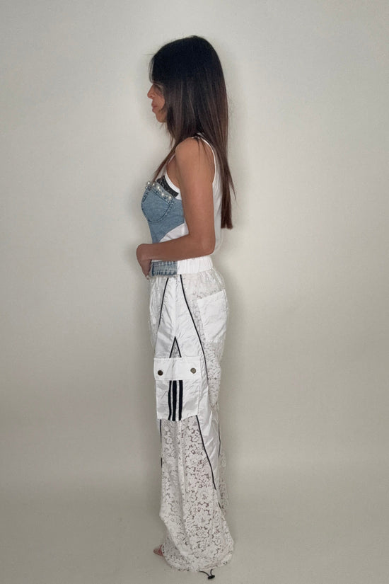 Person wearing a white shirt with black patterns and denim shorts on a plain background Born To Glam