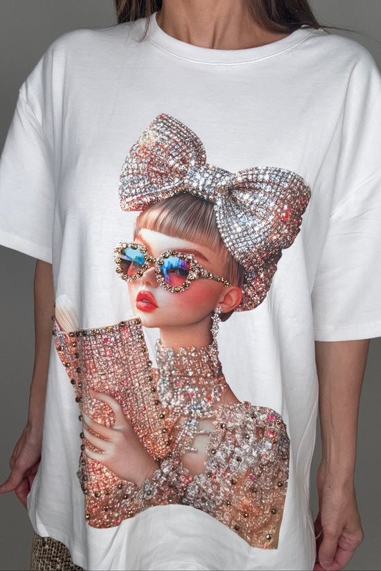 Person wearing a white outfit with a large decorative bow and colorful earrings on a gray background Born To Glam