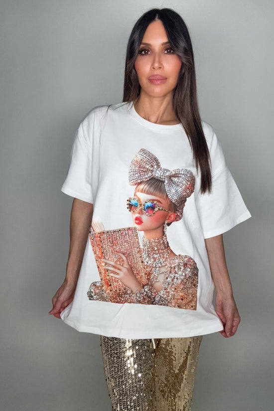 Woman wearing a white t-shirt with a graphic design of a woman holding a clutch. Born To Glam