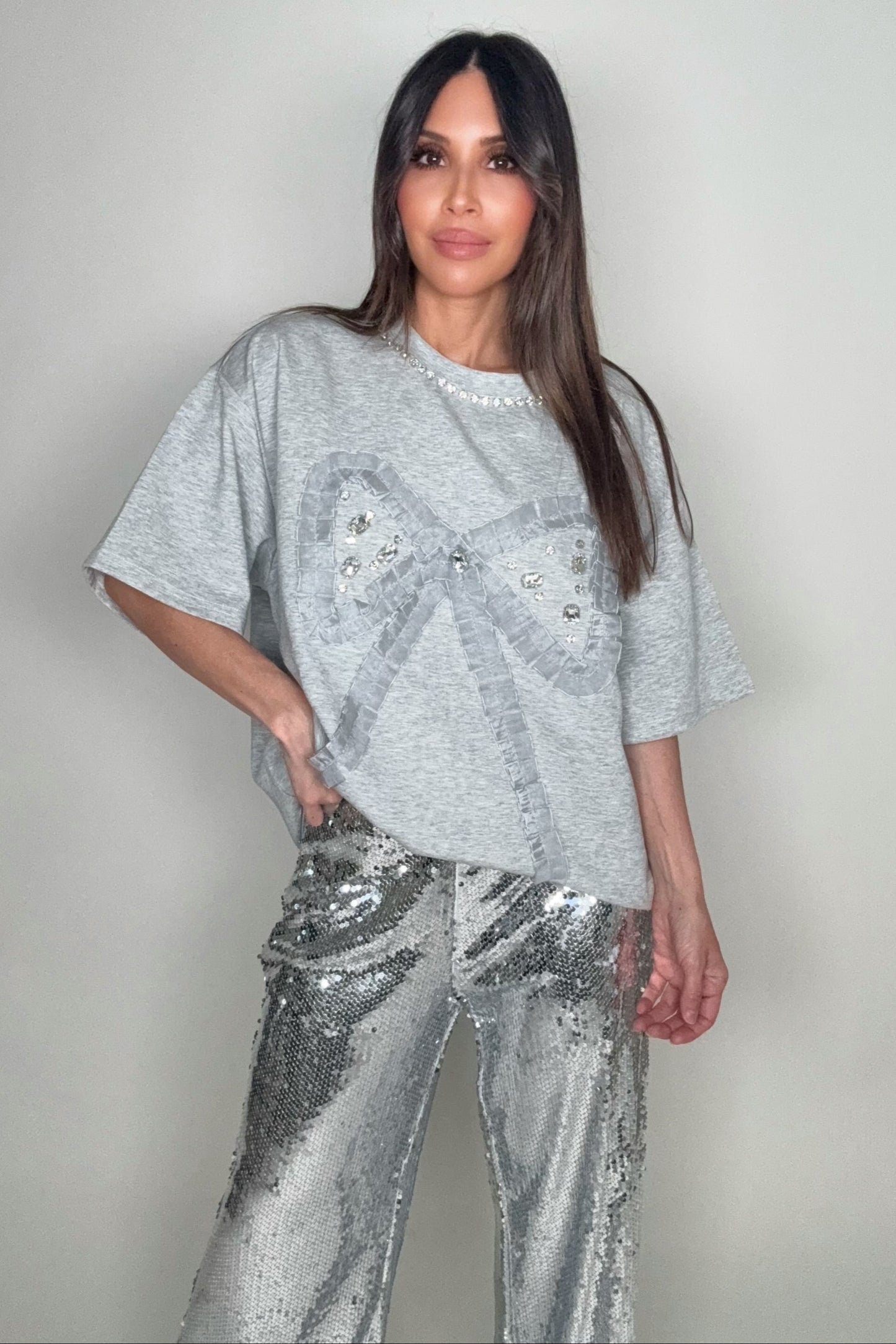 Woman wearing a silver sequin outfit against a plain background Born To Glam