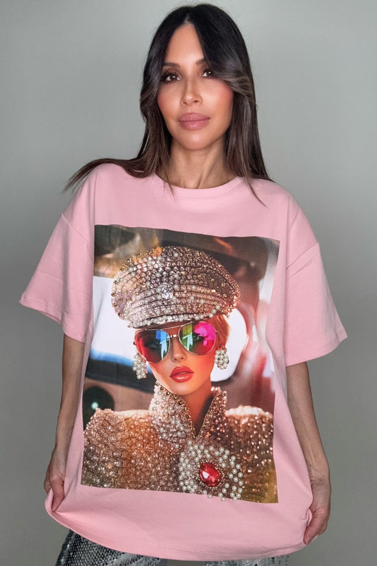 Person wearing a pink t-shirt with a graphic design of a person in a rhinestone outfit. Born To Glam