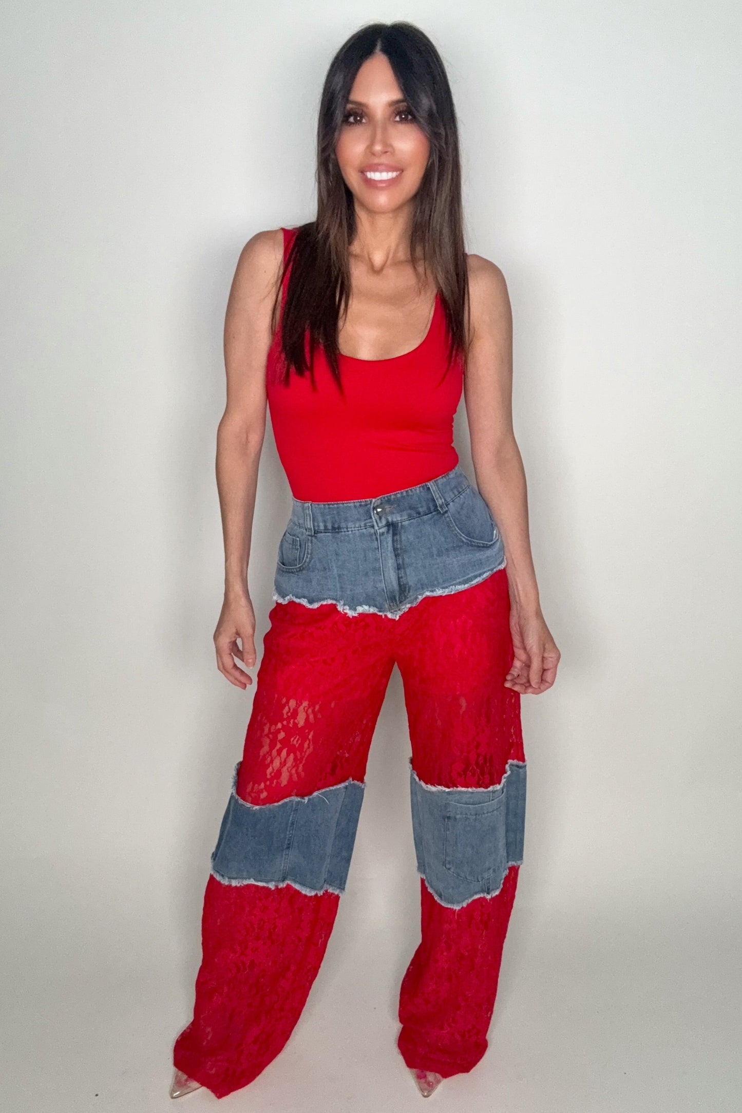 Woman wearing a red top and red and blue patchwork pants on a white background Born To Glam