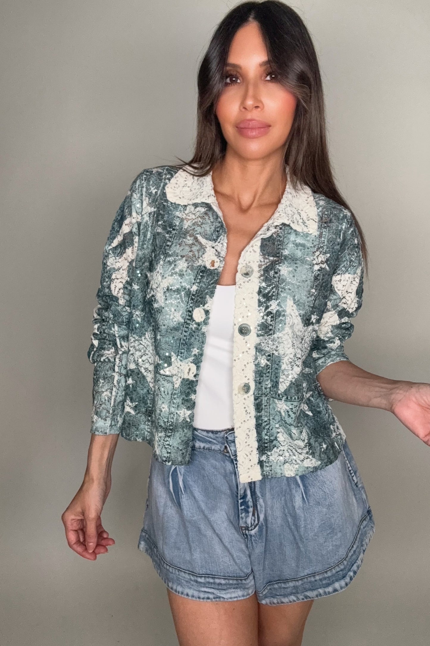 Woman wearing a star jacket and denim shorts against a plain background Born To Glam