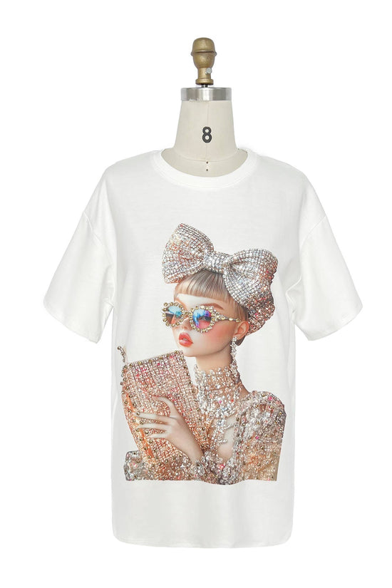 White t-shirt with a graphic of a person wearing sunglasses and a large bow on a mannequin against a white background. Born To Glam