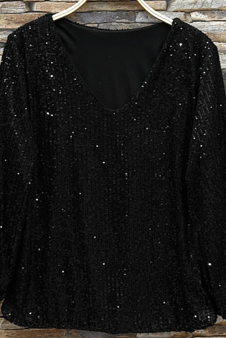 Black sequin top on a hanger against a stone wall background Born To Glam