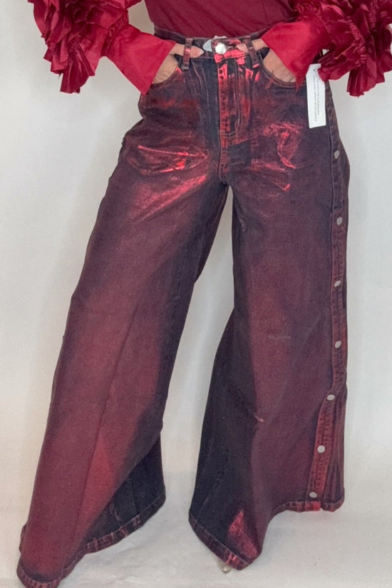 Person wearing a burgundy outfit with ruffled sleeves against a white background Born To Glam